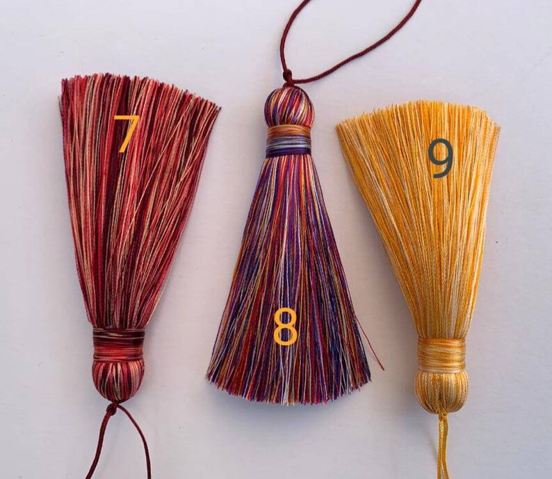May include: Three colourful tassel ornaments with a striped design. The tassels are numbered 7, 8, and 9.