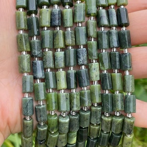 Puede incluir: Una hebra de cuentas de jade verde oscuro con separadores plateados. Las cuentas son rectangulares y tienen una forma ligeramente irregular.