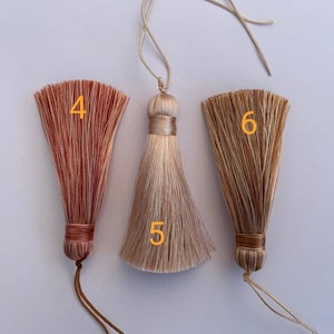 May include: Three tassel ornaments with different colours and patterns. The tassels are made of a soft, silky material and have a long, flowing fringe. The tassels are numbered 4, 5, and 6.