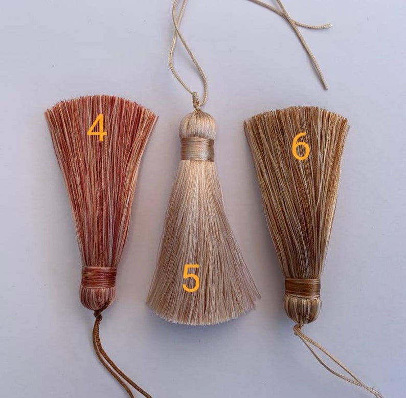 May include: Three tassel ornaments with different colours and patterns. The tassels are made of a soft, silky material and have a long, flowing fringe. The tassels are numbered 4, 5, and 6.