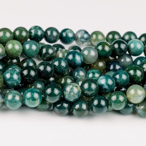 May include: A collection of round, polished moss agate beads featuring deep forest green hues with translucent areas and dark, moss-like inclusions. The beads are arranged in a dense, multi-row cluster, showcasing a smooth, glossy surface finish.