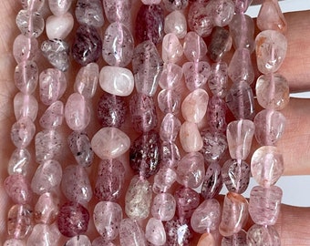 May include: A strand of pink and clear tumbled gemstone beads. The beads are irregularly shaped and have a speckled appearance.