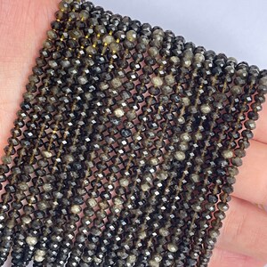 May include: A strand of dark gray faceted gemstone beads. The beads are small and have a shiny, almost metallic finish.