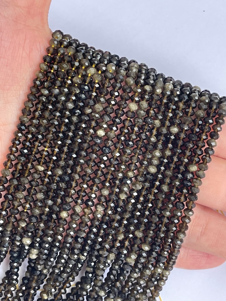 May include: A strand of dark gray faceted gemstone beads. The beads are small and have a shiny, almost metallic finish.