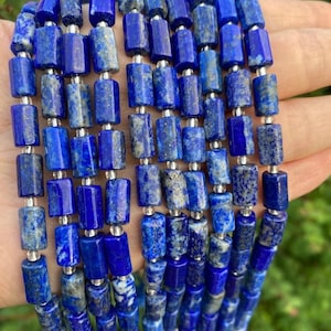 May include: A strand of blue lapis lazuli gemstone beads, each bead is a rectangular prism with silver accents. The beads are arranged in rows, creating a visually appealing pattern.