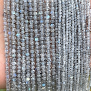 May include: A strand of faceted, iridescent, white labradorite gemstone beads. The beads are strung on a clear thread and are approximately 4mm in diameter.