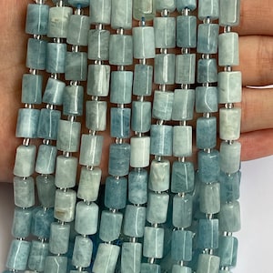 May include: A strand of light blue aquamarine gemstone beads, each bead is a rectangular barrel shape with a smooth, polished finish.
