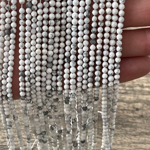 May include: A strand of white and grey Howlite beads, each bead is faceted and has a unique pattern. The beads are strung on a white thread and are approximately 4mm in diameter.