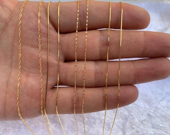 May include: A set of eight gold chains of varying widths and styles, displayed on a hand.