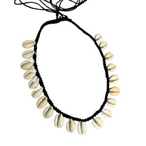 May include: A black cord necklace adorned with multiple cream-colored seashells. The shells are evenly spaced along the cord, creating a symmetrical design. The necklace has an adjustable length with a sliding knot closure.