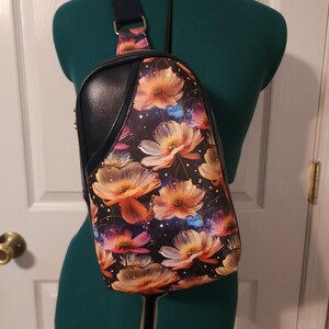 Bolso bandolera Rosie Sling de vinilo azul marino y estampado floral con interior de tejido de algodón dorado ligeramente estructurado.