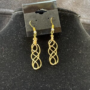 May include: A pair of gold wire earrings with a twisted infinity knot design. The earrings have a simple hook closure.
