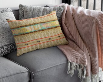 Puede incluir: Un sofá gris con una manta de tiro a rayas rosa y blanca y una almohada decorativa con un patrón geométrico colorido.