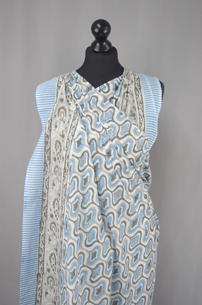 Puede incluir: Bufanda estampada sobre un maniqu&iacute;. La bufanda presenta un dise&ntilde;o geom&eacute;trico repetitivo en tonos azules, grises y blancos. El borde tiene rayas azules y blancas. La bufanda est&aacute; hecha de una tela ligera.
