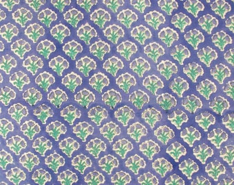 May include: A repeating pattern of stylized floral motifs on a blue background. The flowers are in shades of purple, green, and white, creating a symmetrical and visually appealing design. The overall aesthetic is reminiscent of traditional textile patterns.