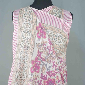 Puede incluir: Una prenda sin mangas, estilo envolvente, con un estampado floral y a rayas. La tela presenta una base blanca con dise&ntilde;os florales rosas y melocot&oacute;n, acentuados por rayas rosas. La prenda se exhibe en un maniqu&iacute; negro.