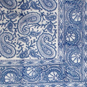 Può includere: Primo piano di un tessuto a fantasia paisley blu e bianco. Il design presenta grandi motivi paisley e dettagli di bordi floreali. Il tessuto ha un motivo dettagliato e intricato.