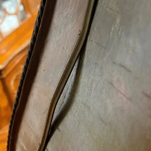 Puede incluir: Primer plano de un marco de madera con un ribete de cuerda. El marco tiene una grieta que recorre el borde superior y una ligera curva en el borde inferior.