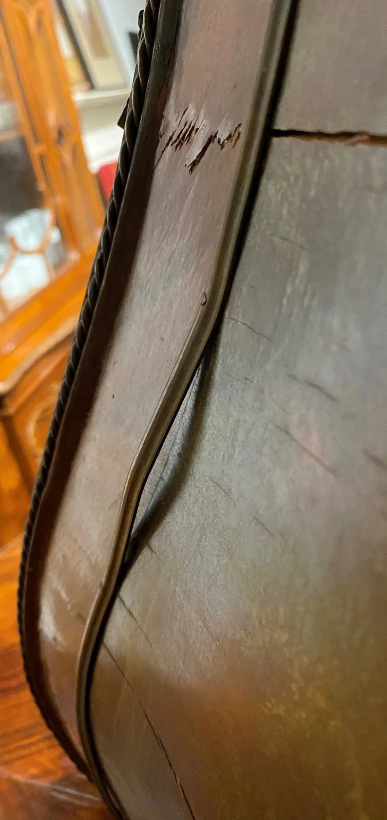 Puede incluir: Primer plano de un marco de madera con un ribete de cuerda. El marco tiene una grieta que recorre el borde superior y una ligera curva en el borde inferior.