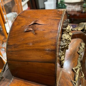 Puede incluir: Un reloj antiguo de madera con adornos dorados y una grieta en la madera. El reloj necesita ser reparado.