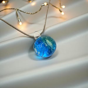 May include: A white ceramic mug with a black handle and the text "But First, Coffee" in a black, handwritten-style font. The mug is on a white surface.