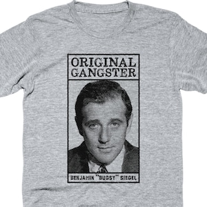 May include: A gray t-shirt featuring a black and white image of Benjamin "Bugsy" Siegel with the text "ORIGINAL GANGSTER". The image is a vintage-style portrait.