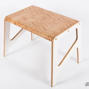 Peut inclure: Une table en bois blanc avec un plateau à motif en chevrons. La table a un design simple et moderne avec des bords arrondis et une finition peinte en blanc.