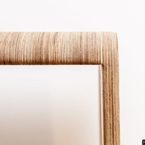 May include: Close-up of a wooden frame made of thin strips of plywood, creating a unique and modern design.