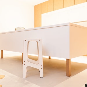 May include: A white kitchen island with a wooden worktop and four wooden legs. A white wooden step stool is in front of the island.