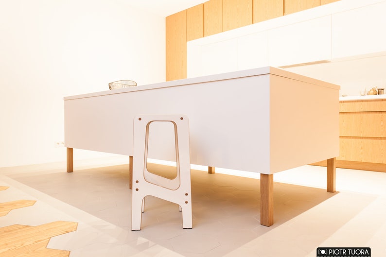 May include: A white kitchen island with a wooden worktop and four wooden legs. A white wooden step stool is in front of the island.
