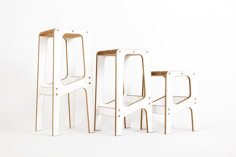May include: Three white wooden stools of varying heights. The stools have a simple, modern design with a rectangular seat and four legs.