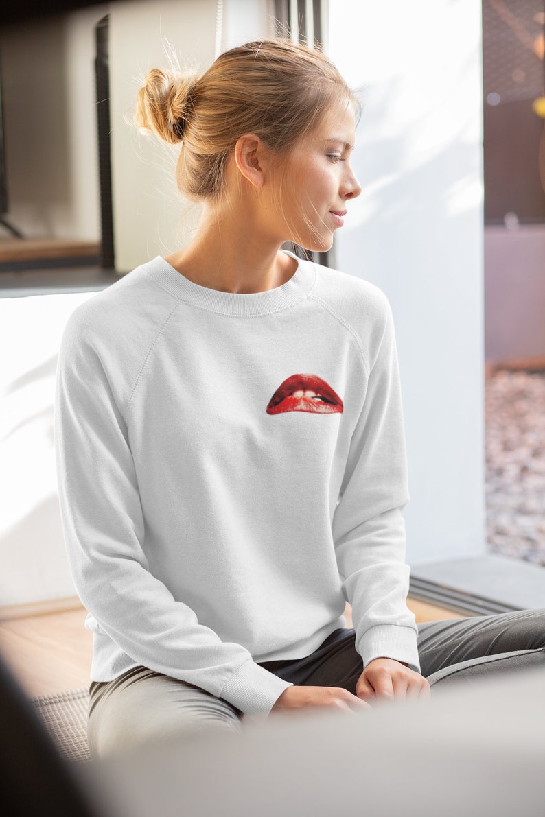 Peut inclure: Sweat-shirt blanc avec un motif rouge et blanc d'une bouche avec des dents sur le devant.