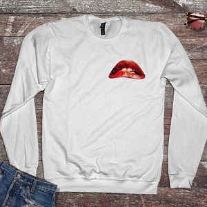 Peut inclure: Sweat-shirt blanc &agrave; manches longues avec un imprim&eacute; de l&egrave;vres rouges ouvertes sur le devant.