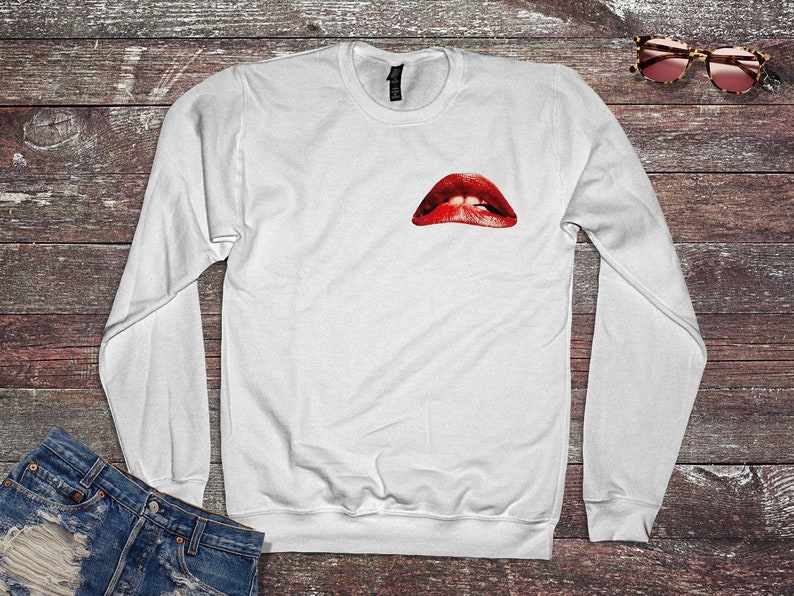 Peut inclure: Sweat-shirt blanc &agrave; manches longues avec un imprim&eacute; de l&egrave;vres rouges ouvertes sur le devant.
