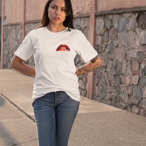 Peut inclure: Un t-shirt blanc avec un motif rouge et blanc de l&egrave;vres sur le devant.