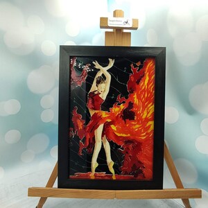 May include: Framed stained glass artwork depicting a dancer in a red dress with a fiery orange background.