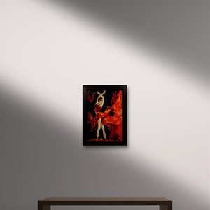 May include: A framed painting of a woman in a red dress dancing with flames behind her. The painting is on a wooden bench in front of a white wall.