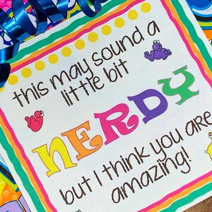 May include: A colorful card with the text "this may sound a little bit NERDY but I think you are amazing!" with a rainbow border and cartoon animals.