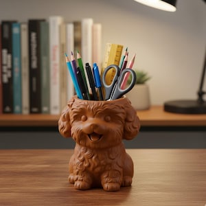May include: A brown dog-shaped desk tidy filled with stationery including pencils, pens, scissors, and a ruler. The organiser is textured and has a smiling face. A bookshelf and desk lamp are in the background.