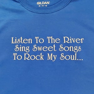 May include: A royal blue t-shirt with the text "Listen To The River Sing Sweet Songs To Rock My Soul..." in a decorative font. The shirt has a crew neck and the Gildan brand label.