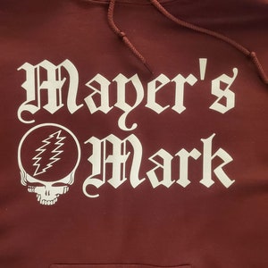 May include: Burgundy hooded sweatshirt with white text that reads "Mayer's Mark" and a white graphic of a skull with lightning bolts.