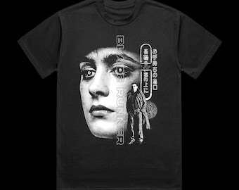 May include: Black t-shirt featuring a grayscale graphic of a woman's face and a man in a coat, with the text "BLADE RUNNER" and Japanese characters. The design is centered on the front of the shirt.