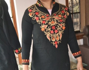 May include: Black long-sleeved tunic with intricate embroidery in shades of orange, red, and gold. The embroidery features floral and paisley designs.