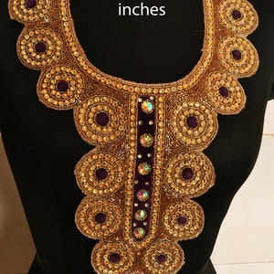 Może przedstawiać: Złota i fioletowa koronkowa ozdoba dekoltu z centralnym pionowym paskiem z fioletowego aksamitu i kryształków. 12 x 17 cali.