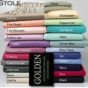 May include: A display of folded stoles in a variety of colours, such as Stone, Canvas, and Champagne. The stoles are stacked, revealing a spectrum of shades from gentle pastels to vivid tones. The word "STOLE" is at the top, and a label reads "GOLDEN CERTIFICATION TRADE MARK PURE NEW PASHMINA."