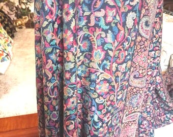 May include: A dark blue shawl featuring an intricate, multi-colored floral and paisley pattern woven throughout. The design includes vibrant shades of pink, teal, light blue, and gold, creating a dense, continuous tapestry of botanical motifs.