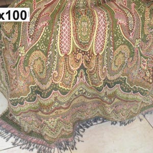 May include: A paisley patterned throw blanket in shades of green, brown, and pink. The blanket measures 56 x 100 inches and has a fringed edge. The design features intricate floral and scroll motifs.