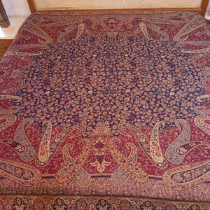 May include: An elaborate bedspread featuring a detailed paisley design in burgundy, navy, and gold. The pattern covers the entire surface, creating a luxurious appearance. The bedspread is displayed on a wooden bed frame. The measurements are in centimeters.
