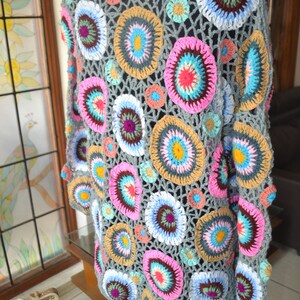 May include: A grey crochet cardigan with a colourful circular pattern. The cardigan is made with a variety of colours, including pink, blue, yellow, and green.
