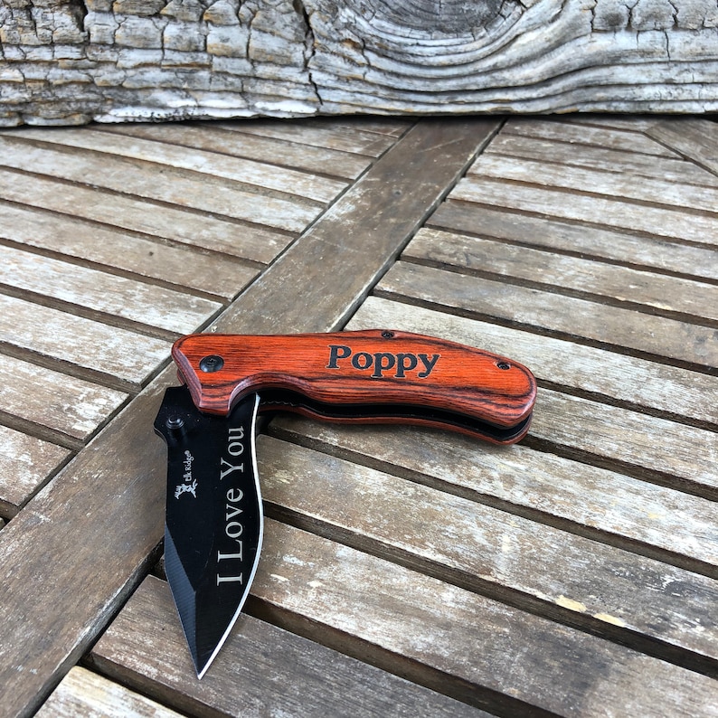 May include: A wooden handled pocket knife with a black blade. The handle is engraved with the words "Poppy" and "I Love You".